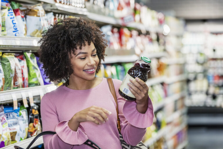 young black woman reading nutrition label on bottle of juice, organic flavor regulations