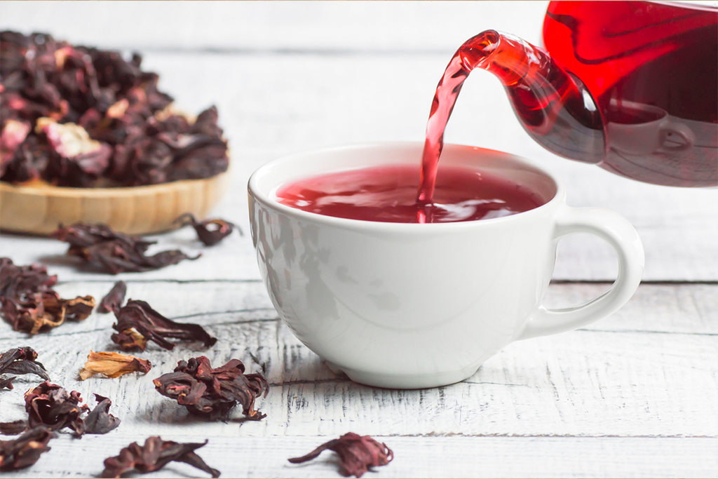 pouring hibiscus tea into tea cup