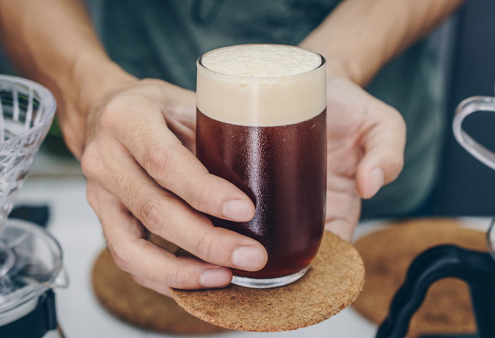 Man holding a glass of nitro cold bre coffee, coffee beverage innovation