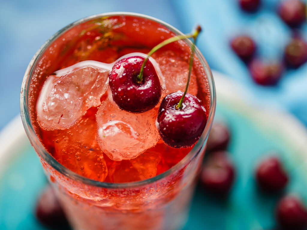 Close Up Of Iced Organic Cherry Lemonade With Fresh Berries On The Blue Table, natural cherry flavor