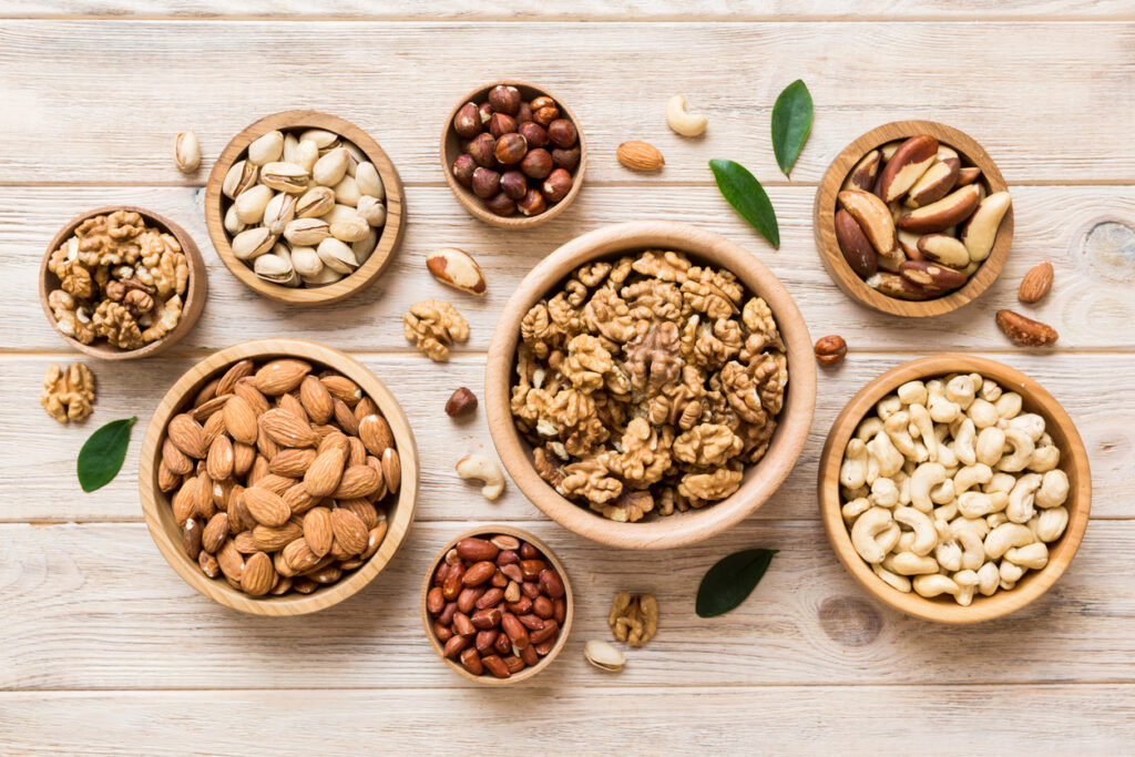 Mixed Nuts In Wooden Bowl. Mix Of Various Nuts On Colored Background. Pistachios, Cashews, Walnuts, Hazelnuts, Peanuts And Brazil Nuts