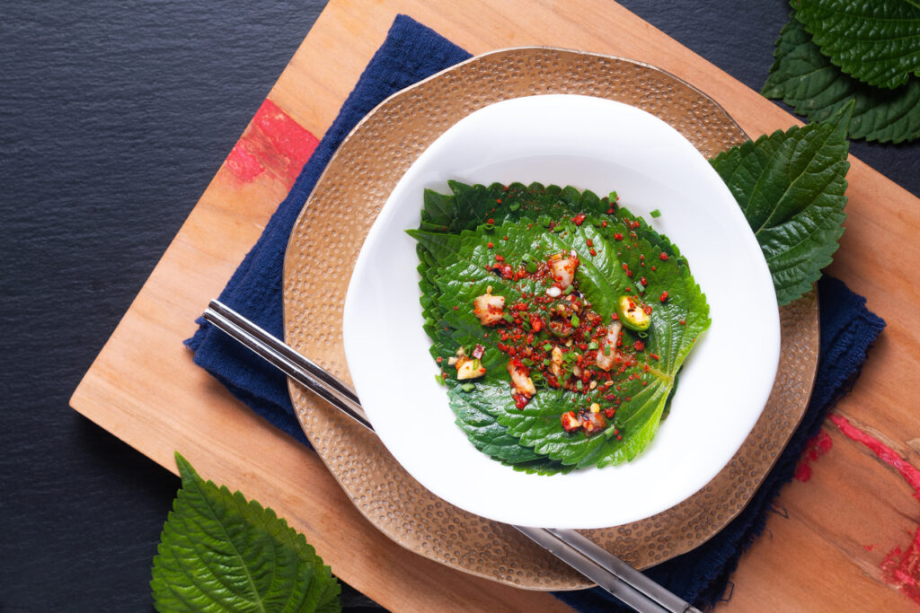 Asian Food Concept Homemade Korean Organic Kkaennip Kimchi, Perilla(shiso) Kimchi In White Ceramic Bowl On Wooden Board With Copy Space