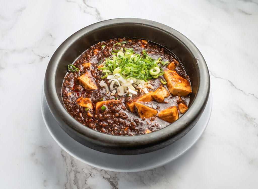 A Bowl Of Savory Koreanstyle Doenjang Jjigae Stew With Tofu And Green Onions On A Marble Table
