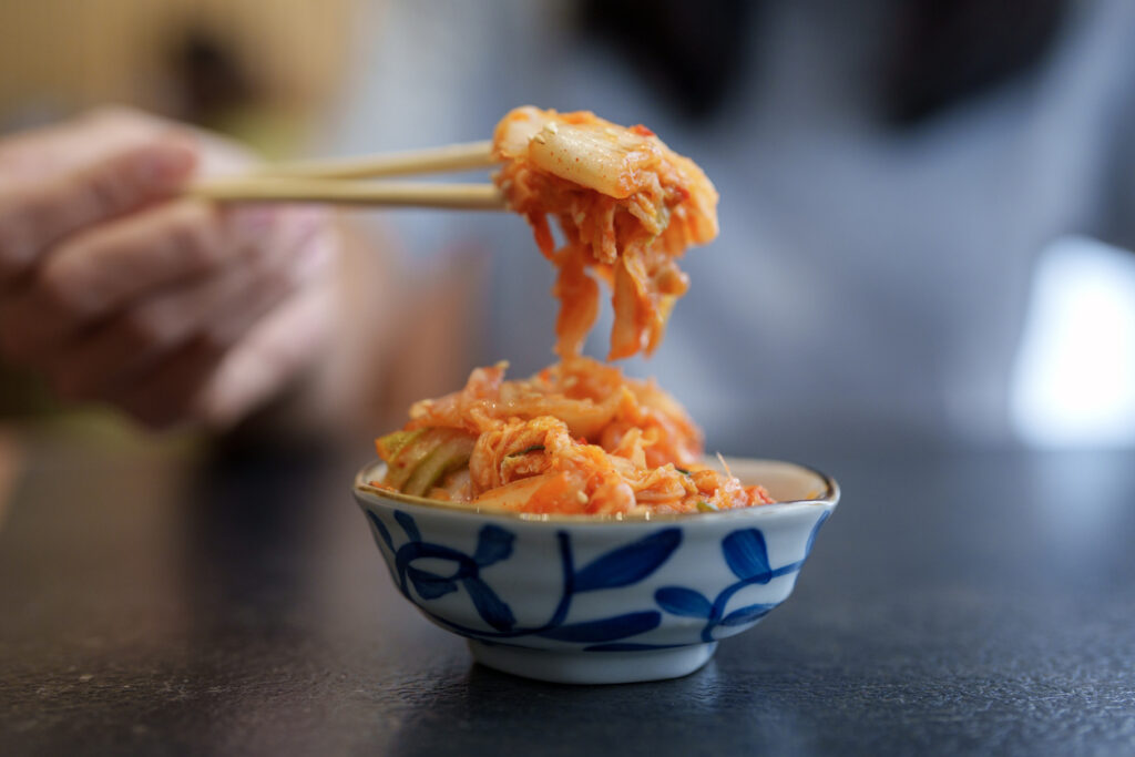 Picking Up Fresh Korean Kimchi With Chopsticks, a naturally fermented postbiotic functional ingredient