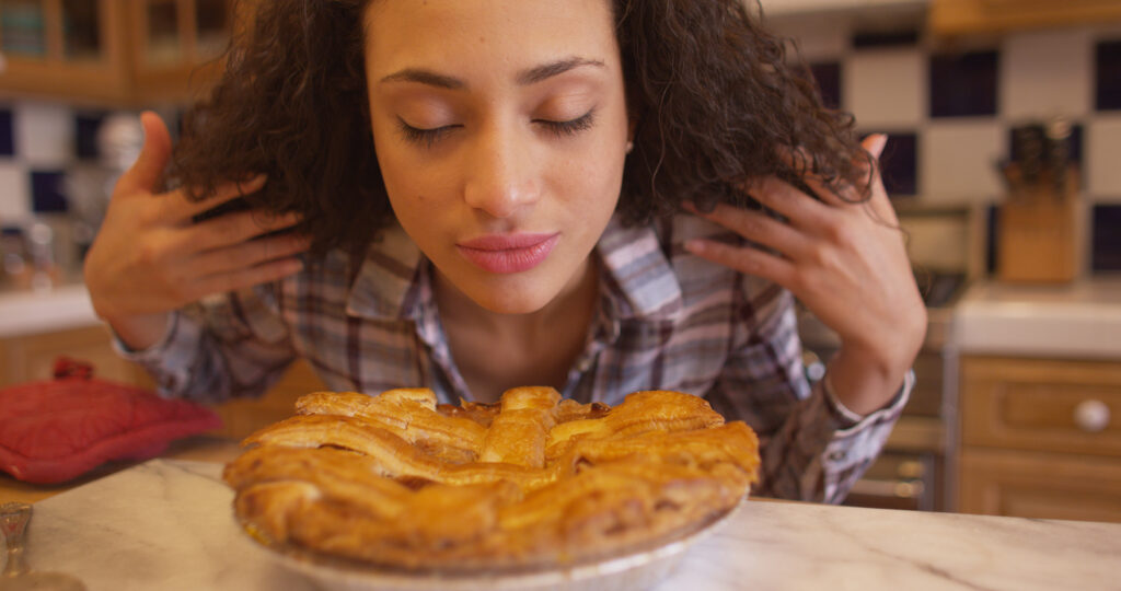 Charming Young Mixed Ethnic Woman Smelling Apple Pie.