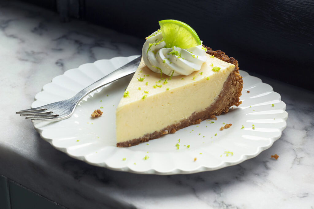 Slice Of Key Lime Pie With Whipped Cream And Lime Zest On A Plate