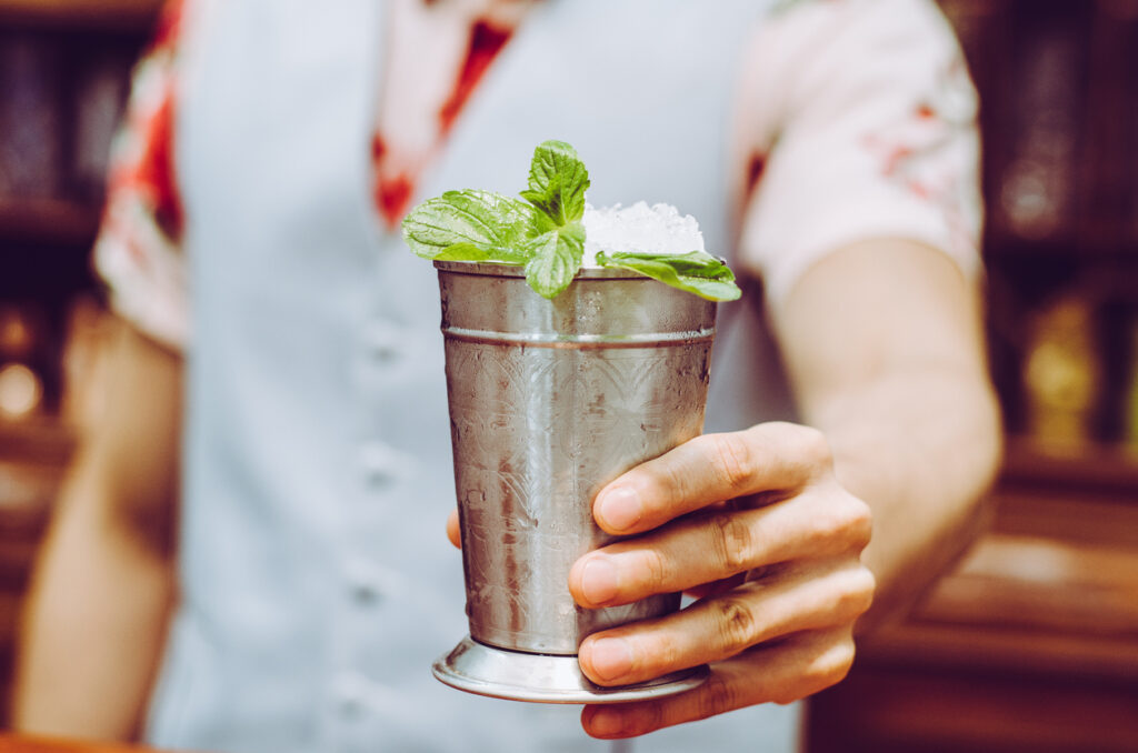 Bartender Preparing Delicious Mint Julep Cocktail At Table.
