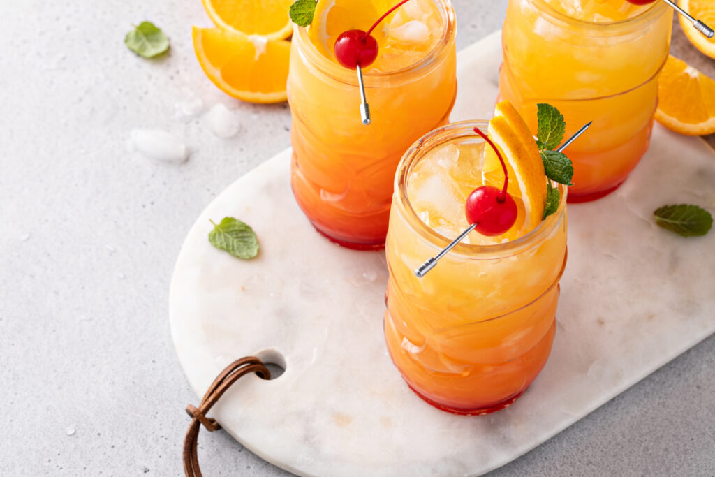 Hurricane Cocktail In Tiki Glasses, Tropical, Rum Based Cocktail With Orange And Cherry For Garnish